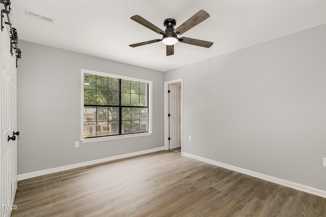 7708 Falcon Rest Cir, Raleigh, NC 27615 - empty room featuring a ceiling fan, wood finished floors, and a barn door