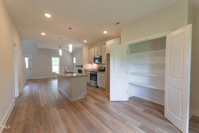 202 E S St, Fremont, NC 27830 - kitchen featuring appliances with stainless steel finishes, light wood-style flooring, recessed lighting, a center island with sink, and light stone countertops