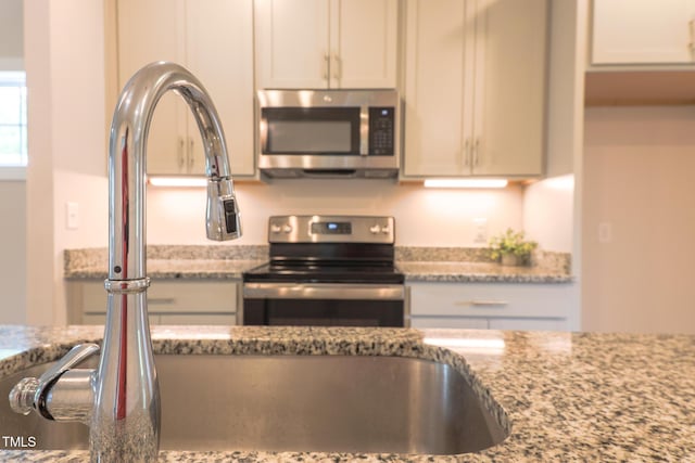 202 E S St, Fremont, NC 27830 - kitchen with appliances with stainless steel finishes, light stone countertops, and white cabinetry