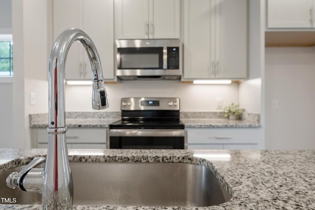202 E S St, Fremont, NC 27830 - kitchen with stainless steel appliances, light stone counters, and white cabinetry