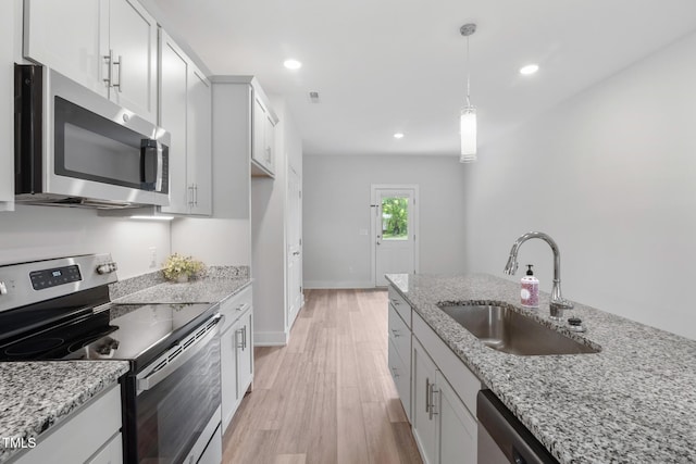 202 E S St, Fremont, NC 27830 - kitchen with appliances with stainless steel finishes, light wood finished floors, hanging light fixtures, light stone countertops, and recessed lighting