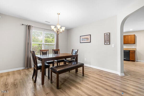 2011 Unbridled Dr, Knightdale, NC 27545 - dining space with light wood-style flooring, baseboards, a chandelier, and arched walkways