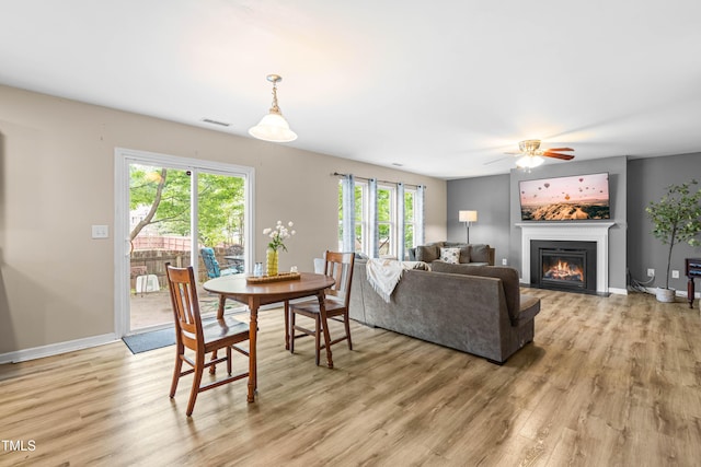 2011 Unbridled Dr, Knightdale, NC 27545 - dining area with light wood finished floors, a glass covered fireplace, ceiling fan, and baseboards