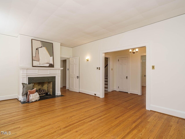 907 W Johnson St, Raleigh, NC 27605 - unfurnished living room featuring a fireplace with flush hearth, a chandelier, light wood-style flooring, and stairway