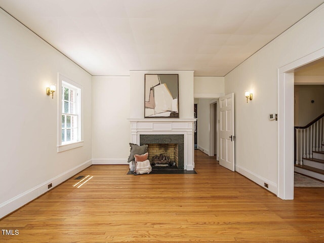 907 W Johnson St, Raleigh, NC 27605 - unfurnished living room featuring a fireplace with flush hearth, light wood-style flooring, and stairway