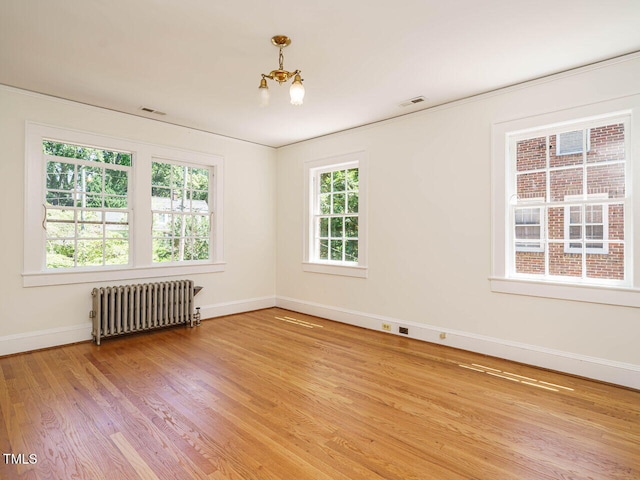 907 W Johnson St, Raleigh, NC 27605 - unfurnished room with radiator heating unit, a chandelier, and wood finished floors