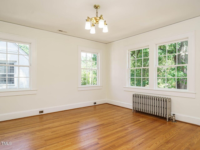 907 W Johnson St, Raleigh, NC 27605 - spare room featuring radiator heating unit, a chandelier, healthy amount of natural light, and light wood-style floors