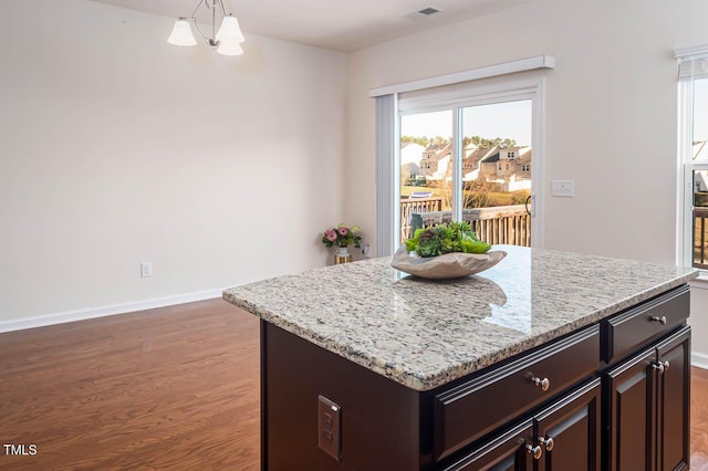 732 Suffield Way, Cary, NC 27519 - kitchen with a chandelier, light wood-style floors, dark brown cabinetry, light stone countertops, and a kitchen island
