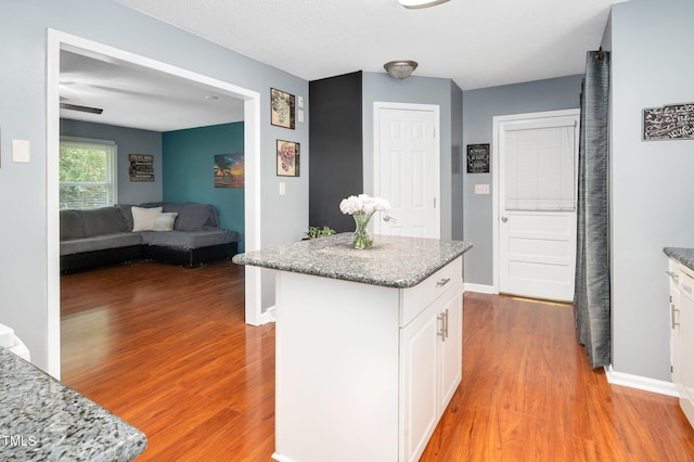 202 Howland Ave, Cary, NC 27513 - kitchen with light wood-style flooring, white cabinets, a kitchen island, light stone countertops, and open floor plan