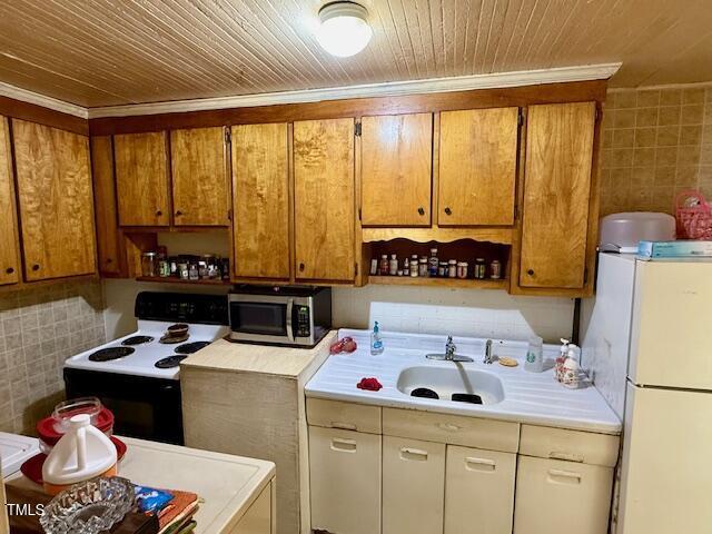 981 Leasburg Rd, Roxboro, NC 27573 - kitchen with stainless steel microwave, freestanding refrigerator, electric range oven, light countertops, and tile walls