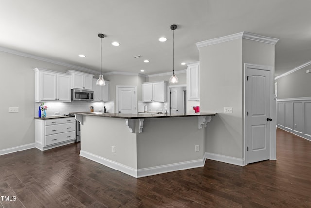 427 Cedar Pond Ct, Knightdale, NC 27545 - kitchen with stainless steel microwave, a breakfast bar area, white cabinets, dark countertops, and dark wood-style flooring