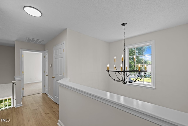 103 Burham Ct, Apex, NC 27502 - hall with light wood-type flooring, an upstairs landing, a chandelier, and a textured ceiling