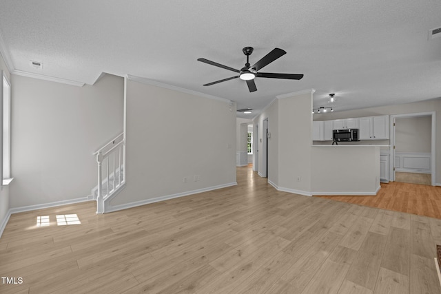 103 Burham Ct, Apex, NC 27502 - unfurnished living room with a textured ceiling, crown molding, light wood-type flooring, ceiling fan, and stairway