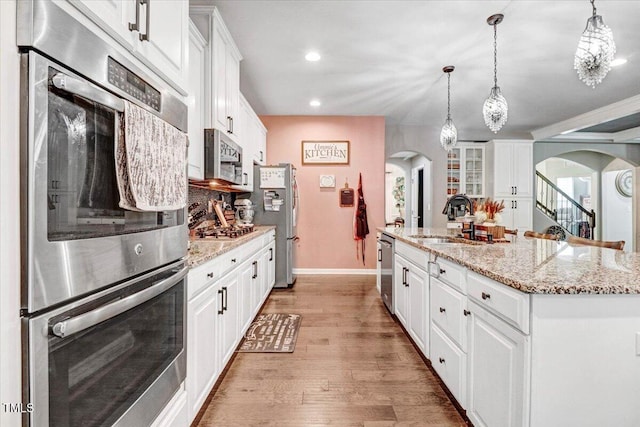728 Opposition Way, Wake Forest, NC 27587 - kitchen with arched walkways, white cabinets, stainless steel appliances, recessed lighting, and light wood-type flooring