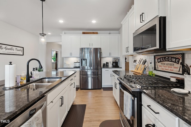 1104 Briar Gate Dr, Holly Springs, NC 27540 - kitchen with appliances with stainless steel finishes, light wood-style flooring, white cabinetry, and recessed lighting