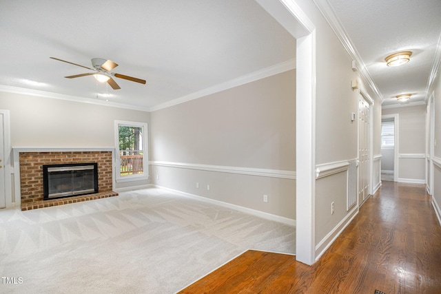 2629 Hiking Trl, Raleigh, NC 27615 - unfurnished living room featuring a ceiling fan, crown molding, a brick fireplace, and wood finished floors