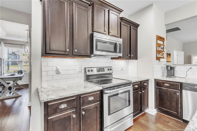 3426 Winnants Ct, Fayetteville, NC 28306 - kitchen with stainless steel appliances, light wood finished floors, dark brown cabinetry, light stone countertops, and decorative backsplash