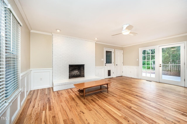 3913 Littlefield Ct, Raleigh, NC 27606 - unfurnished living room featuring light wood-style flooring, a brick fireplace, crown molding, ceiling fan, and a decorative wall