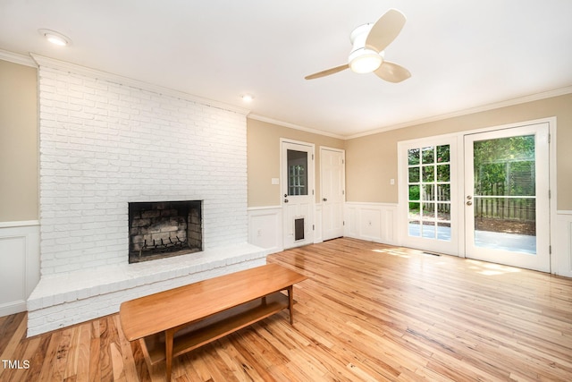 3913 Littlefield Ct, Raleigh, NC 27606 - unfurnished living room with ornamental molding, a fireplace, a ceiling fan, a wainscoted wall, and light wood-style flooring