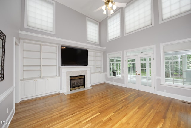4217 Grahamstone Rd, Raleigh, NC 27610 - unfurnished living room with a ceiling fan, a towering ceiling, french doors, built in shelves, and light wood-style flooring