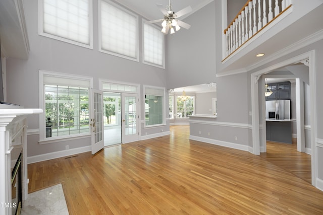 4217 Grahamstone Rd, Raleigh, NC 27610 - unfurnished living room featuring ceiling fan, a fireplace with flush hearth, light wood-type flooring, a high ceiling, and a chandelier
