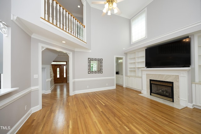 4217 Grahamstone Rd, Raleigh, NC 27610 - unfurnished living room with a ceiling fan, wood finished floors, a fireplace, built in shelves, and a high ceiling