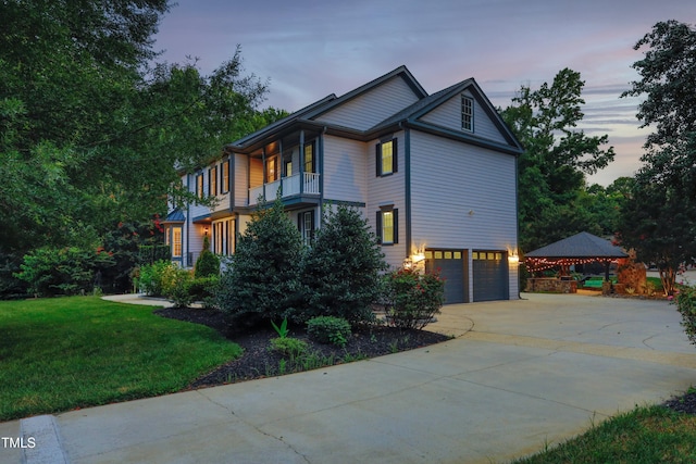 4217 Grahamstone Rd, Raleigh, NC 27610 - property exterior at dusk featuring a balcony, an attached garage, concrete driveway, and a yard