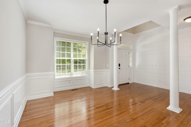 1304 Trailing Rose Ct, Wake Forest, NC 27587 - unfurnished dining area with a chandelier, light wood finished floors, ornamental molding, ornate columns, and a decorative wall