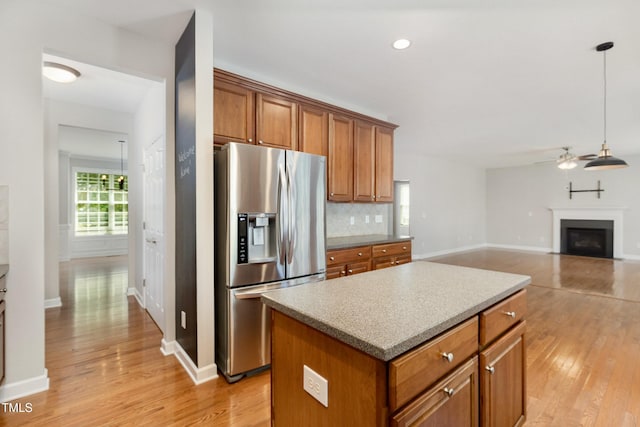 1304 Trailing Rose Ct, Wake Forest, NC 27587 - kitchen featuring stainless steel fridge, ceiling fan, brown cabinets, light wood-type flooring, and decorative backsplash