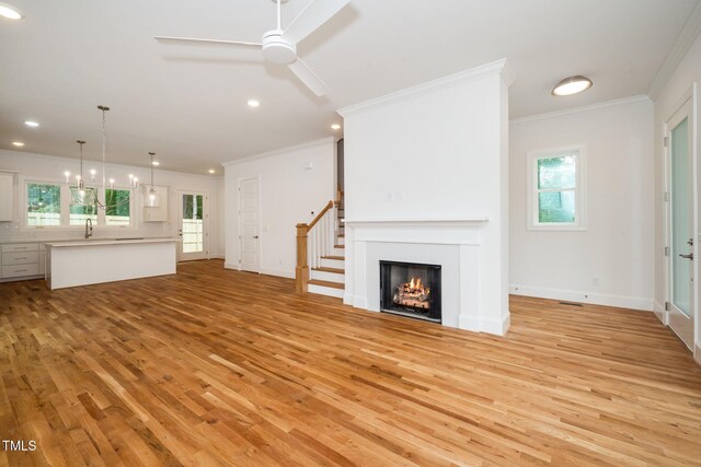 905 Deboy St, Raleigh, NC 27606 - unfurnished living room with ornamental molding, light wood-type flooring, a ceiling fan, a lit fireplace, and recessed lighting