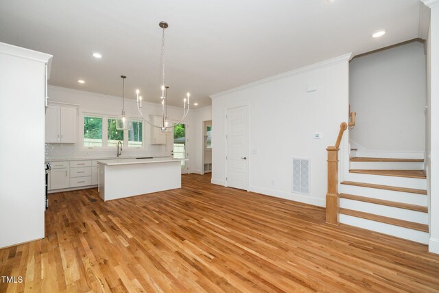 905 Deboy St, Raleigh, NC 27606 - kitchen featuring light wood-style floors, a chandelier, light countertops, tasteful backsplash, and a kitchen island