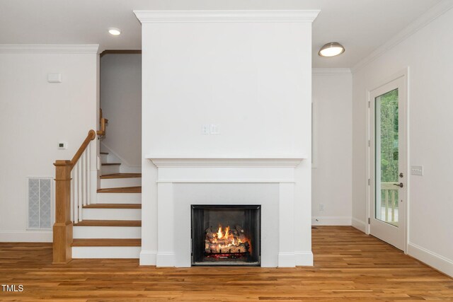 905 Deboy St, Raleigh, NC 27606 - unfurnished living room with wood finished floors, a warm lit fireplace, crown molding, stairway, and recessed lighting