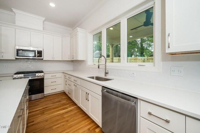 905 Deboy St, Raleigh, NC 27606 - kitchen featuring appliances with stainless steel finishes, ornamental molding, backsplash, white cabinets, and recessed lighting