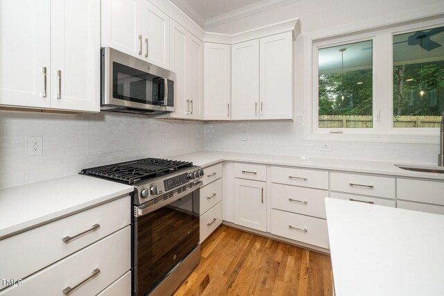 905 Deboy St, Raleigh, NC 27606 - kitchen with stainless steel appliances, light countertops, white cabinetry, decorative backsplash, and ornamental molding