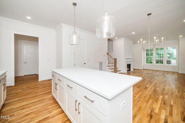 905 Deboy St, Raleigh, NC 27606 - kitchen featuring light wood-style flooring, crown molding, light countertops, a kitchen island, and white cabinetry