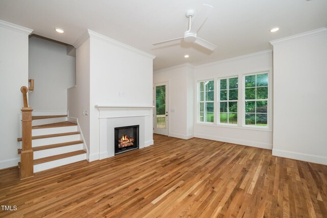 905 Deboy St, Raleigh, NC 27606 - unfurnished living room featuring light wood finished floors, a ceiling fan, crown molding, a lit fireplace, and stairway