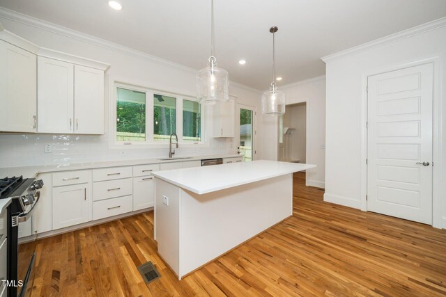 905 Deboy St, Raleigh, NC 27606 - kitchen with range with gas stovetop, ornamental molding, a center island, light wood-style floors, and light countertops