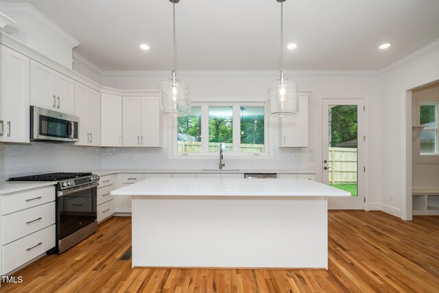 905 Deboy St, Raleigh, NC 27606 - kitchen featuring appliances with stainless steel finishes, ornamental molding, light countertops, a kitchen island, and white cabinetry