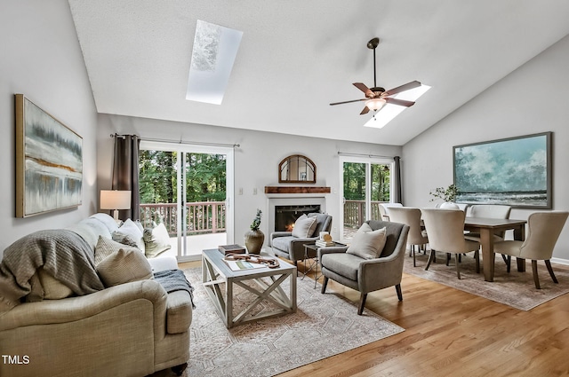 311 Westbrook Dr, Carrboro, NC 27510 - living area featuring a skylight, lofted ceiling, light wood-type flooring, a lit fireplace, and a ceiling fan