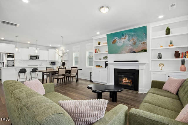 513 Basin Hill Dr, Wake Forest, NC 27587 - living area featuring dark wood-type flooring, recessed lighting, a chandelier, a glass covered fireplace, and built in shelves
