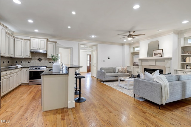 1217 Chalk Maple Dr, Cary, NC 27519 - kitchen with stainless steel gas range, a kitchen breakfast bar, ornamental molding, under cabinet range hood, and a fireplace