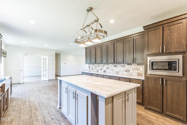 589 Atkinson Mill Rd, Selma, NC 27576 - kitchen with stainless steel microwave, tasteful backsplash, light countertops, light wood finished floors, and a center island