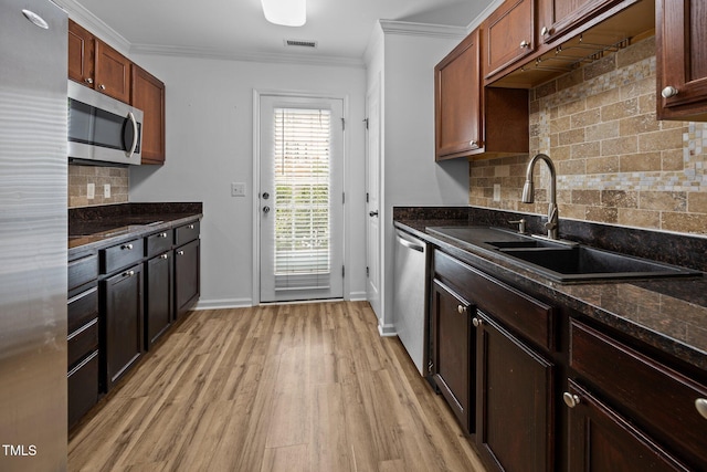 9908 Jerome Ct, Raleigh, NC 27617 - kitchen featuring stainless steel appliances, backsplash, light wood-style flooring, crown molding, and dark stone countertops