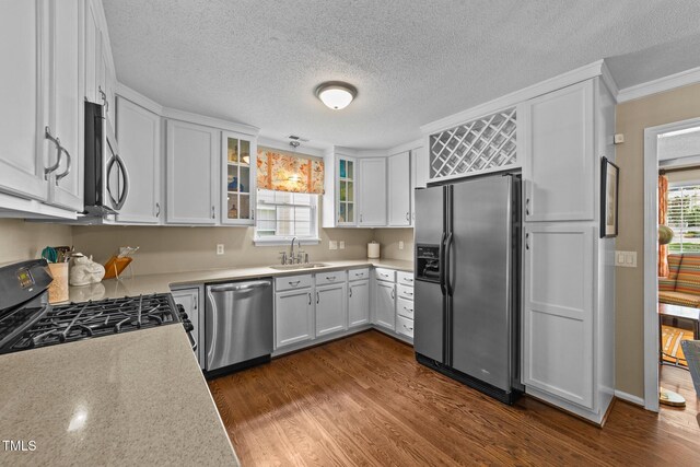 1033 Mills St, Raleigh, NC 27608 - kitchen with stainless steel appliances, light countertops, white cabinetry, crown molding, and dark wood finished floors