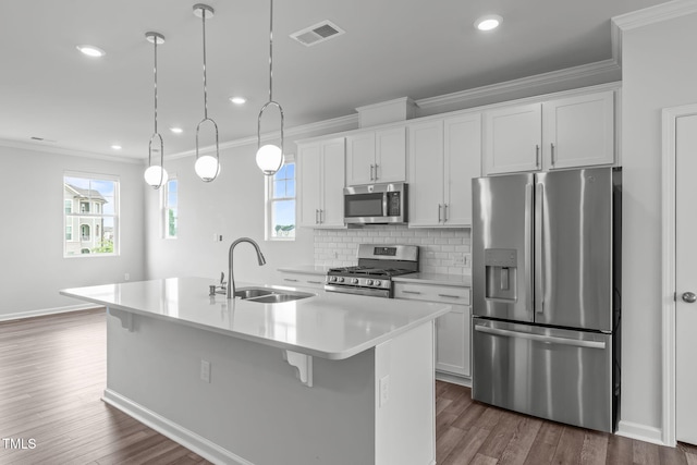 2539 Kasota Ln, Raleigh, NC 27610 - kitchen with stainless steel appliances, ornamental molding, an island with sink, dark wood-style floors, and white cabinets