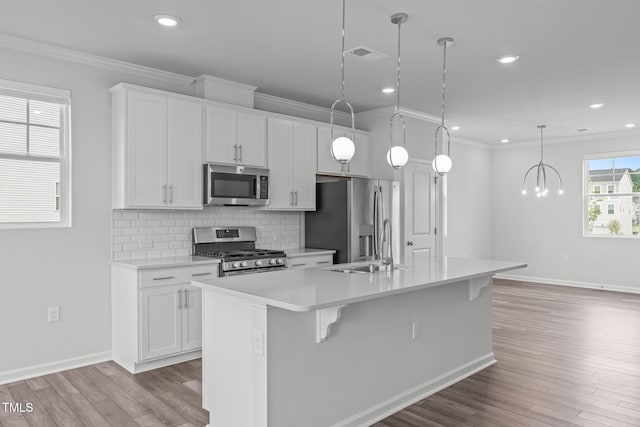 2539 Kasota Ln, Raleigh, NC 27610 - kitchen featuring appliances with stainless steel finishes, a kitchen island with sink, light countertops, crown molding, and white cabinetry