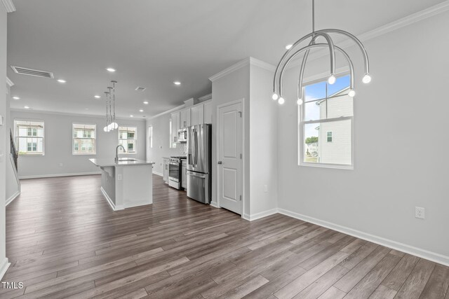 2539 Kasota Ln, Raleigh, NC 27610 - kitchen featuring appliances with stainless steel finishes, ornamental molding, dark wood-type flooring, an island with sink, and white cabinets