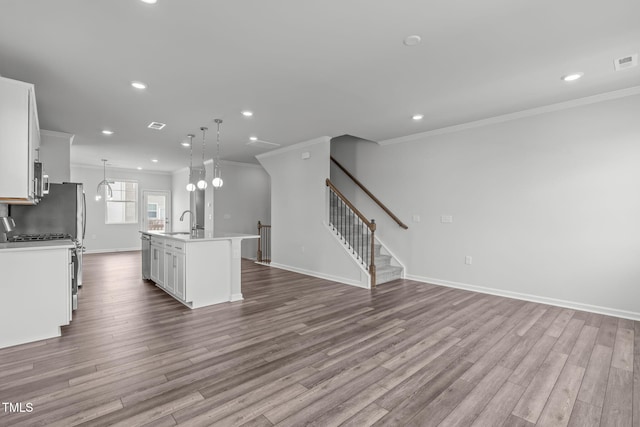 2539 Kasota Ln, Raleigh, NC 27610 - kitchen with appliances with stainless steel finishes, crown molding, a center island with sink, open floor plan, and wood finished floors