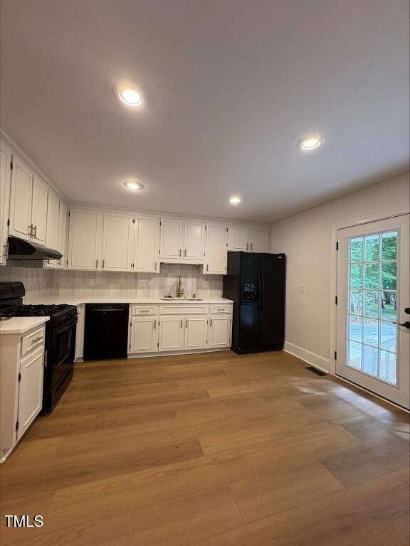 1300 Seabrook Ave, Cary, NC 27511 - kitchen featuring black appliances, under cabinet range hood, white cabinets, decorative backsplash, and recessed lighting