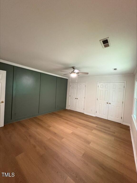 1300 Seabrook Ave, Cary, NC 27511 - unfurnished bedroom with ornamental molding, light wood finished floors, two closets, and a ceiling fan